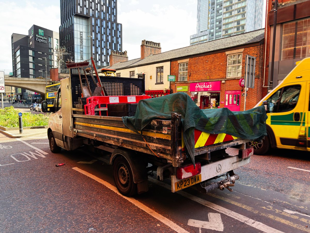 A utility truck carrying barriers and tools parked on a street